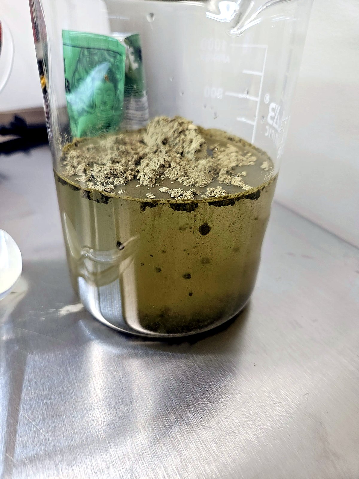 Kratom powder breaking apart and sinking in clumps, clouding the water olive-green within minutes.