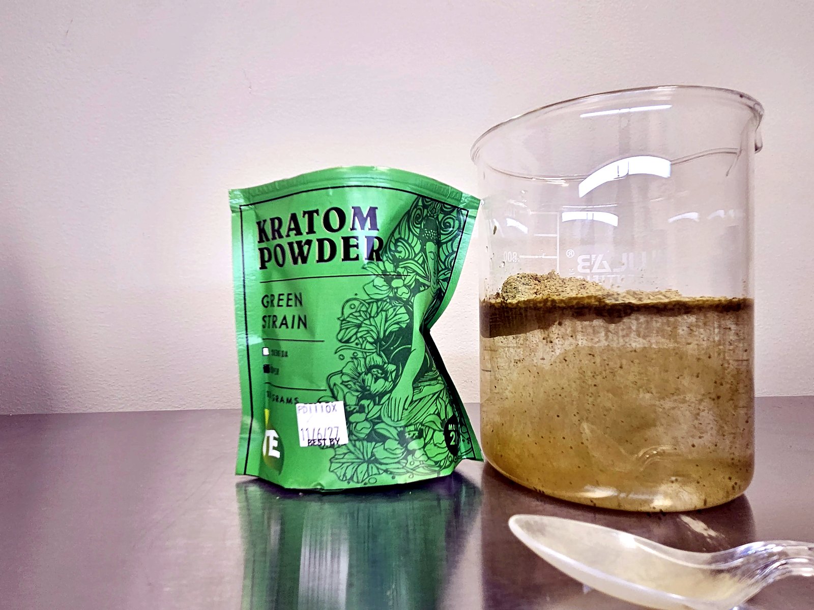 Green kratom powder floating as a dry raft on the surface of clear water.
