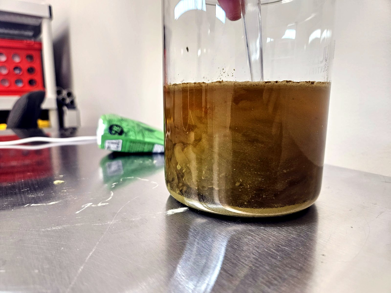Stirred kratom re-clouding the water into a thin, silky suspension, with gritty texture visible on the spoon.
